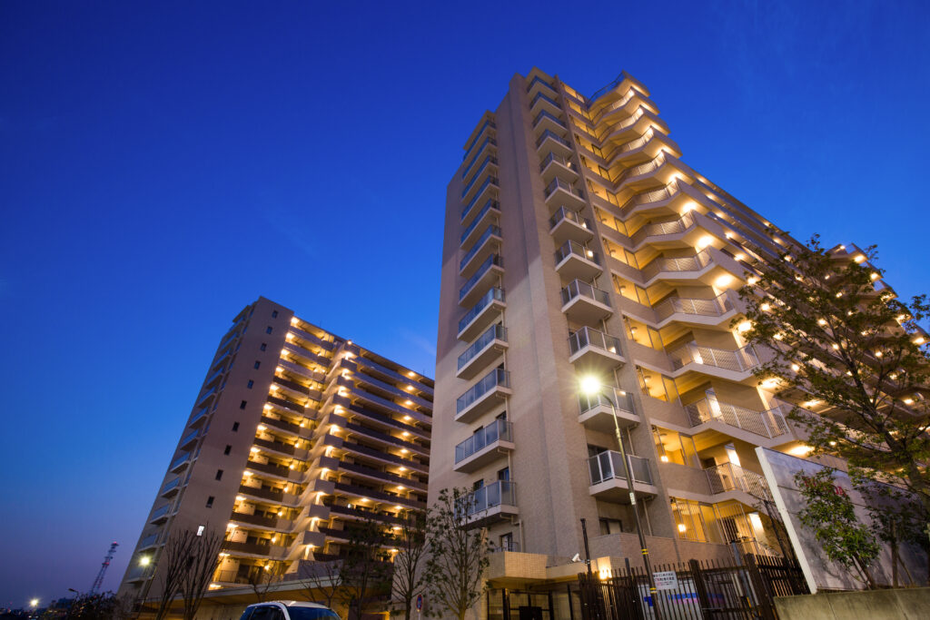 Prédio residencial iluminado ao entardecer com diversas varandas, representando condomínios verticais urbanos que podem adotar energia solar para reduzir custos com eletricidade nas áreas comuns.