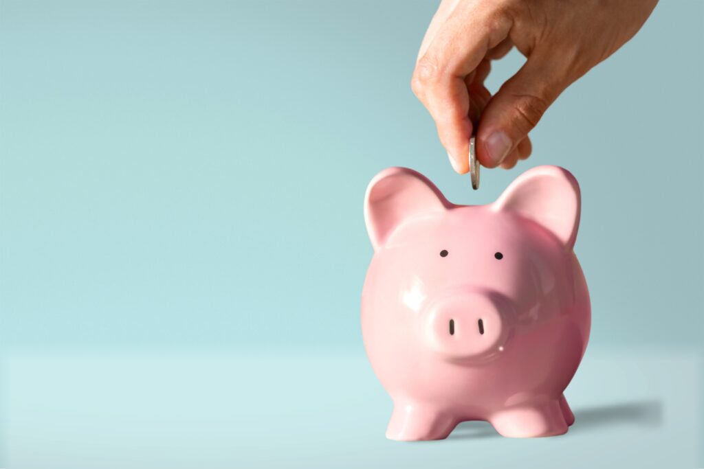 Pessoa economizando dinheiro em um cofrinho rosa, representando o impacto do aumento na conta de luz e a busca por alternativas para reduzir os custos de energia elétrica.