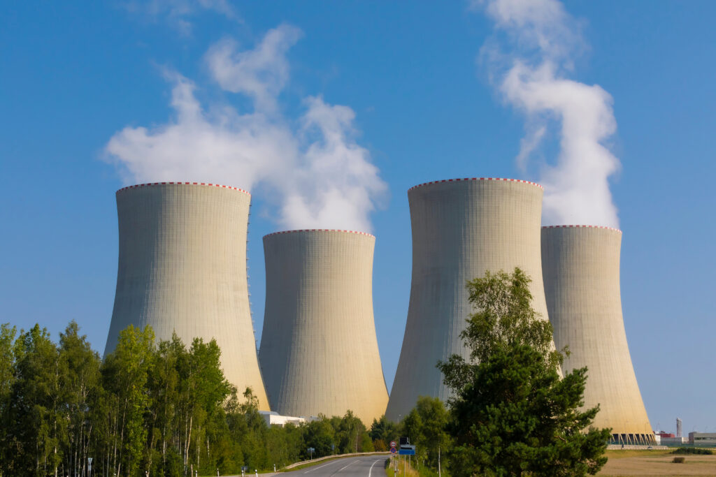 Usina nuclear com torres de resfriamento ativas, simbolizando a busca por energia limpa e constante por parte de empresas como Microsoft e Amazon.
