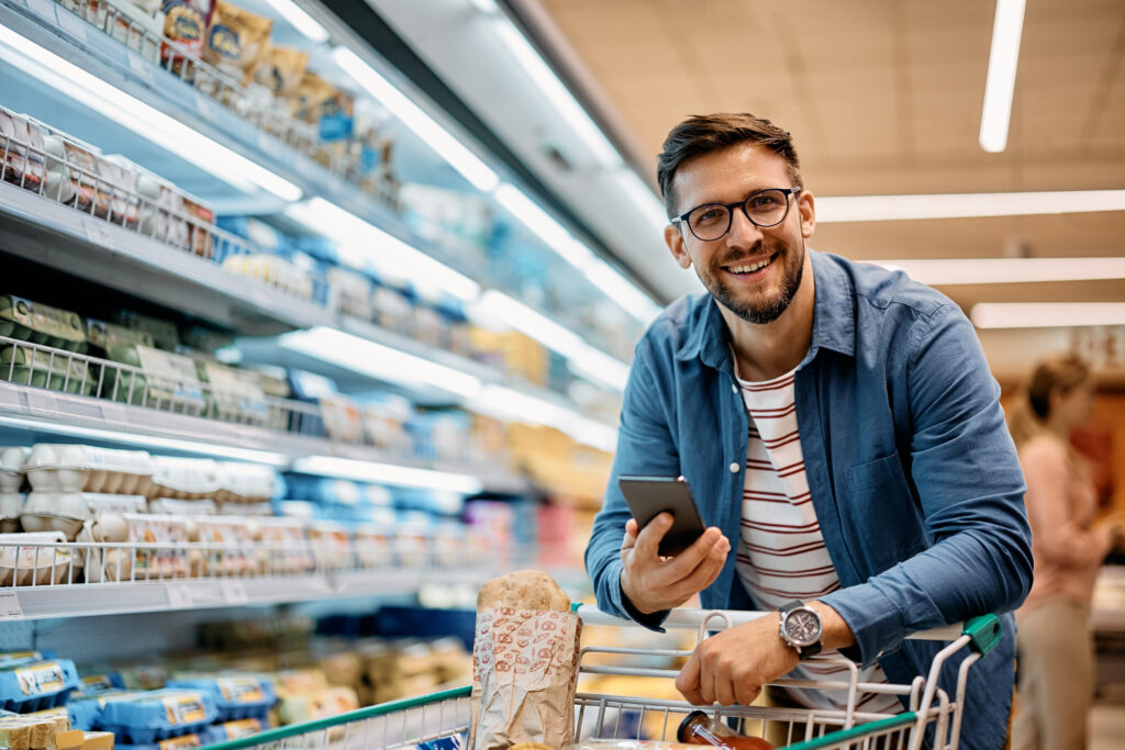 Homem com carrinho em supermercado, simbolizando gestão eficiente e estratégias para economizar energia em supermercado.