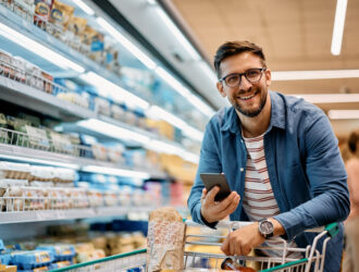 Homem com carrinho em supermercado, simbolizando gestão eficiente e estratégias para economizar energia em supermercado.
