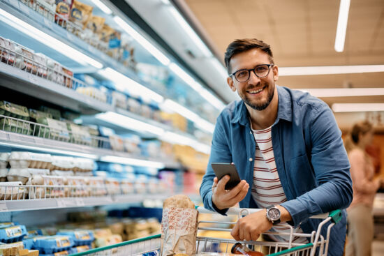 Homem com carrinho em supermercado, simbolizando gestão eficiente e estratégias para economizar energia em supermercado.