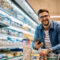 Homem com carrinho em supermercado, simbolizando gestão eficiente e estratégias para economizar energia em supermercado.