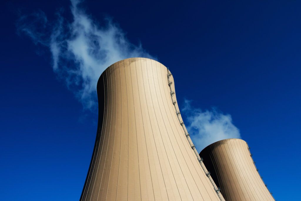 Torres de resfriamento de uma usina nuclear com vapor visível, simbolizando a energia limpa e contínua buscada por empresas como Amazon e Microsoft.